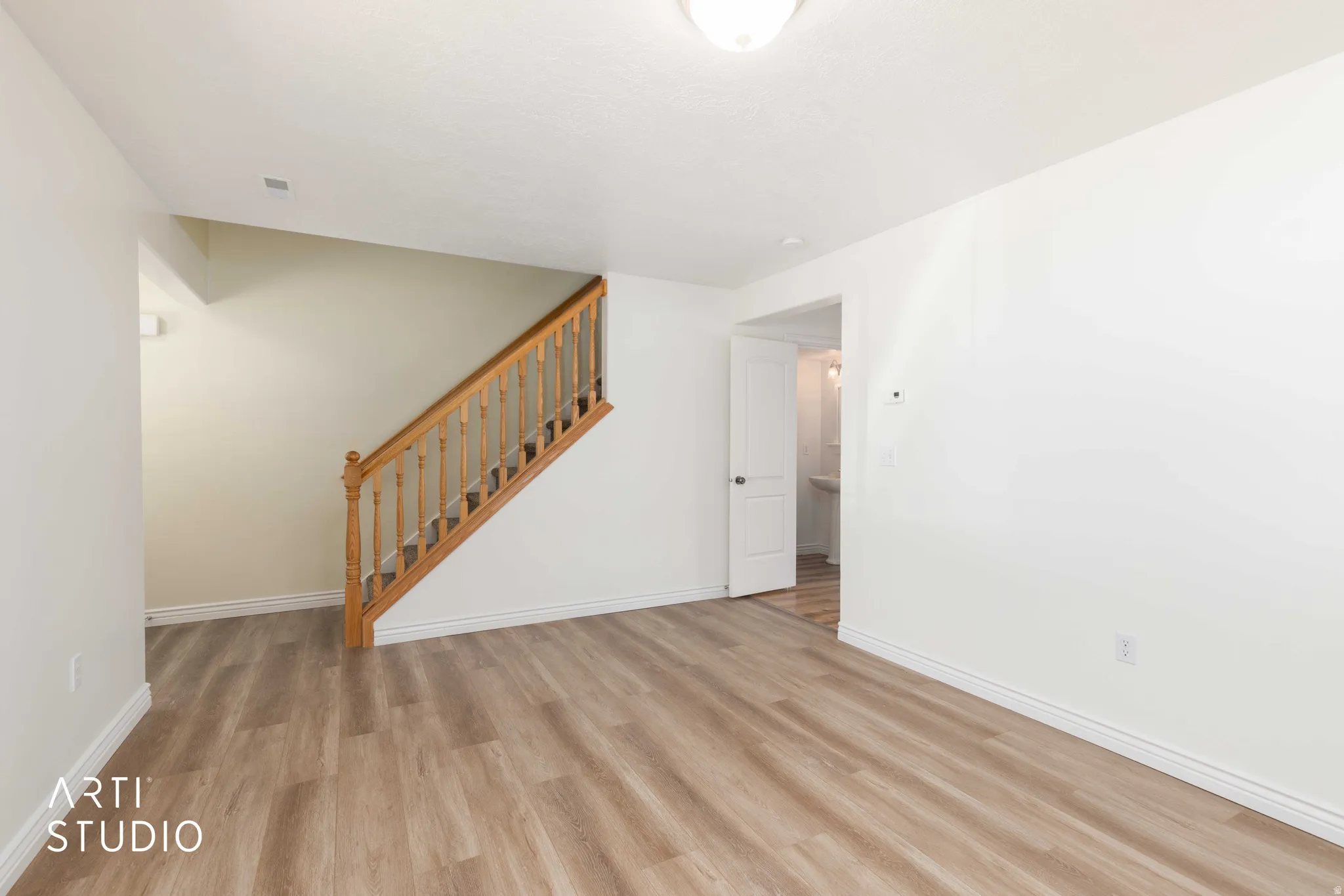 Unfurnished living room featuring stairway and light wood finished floors