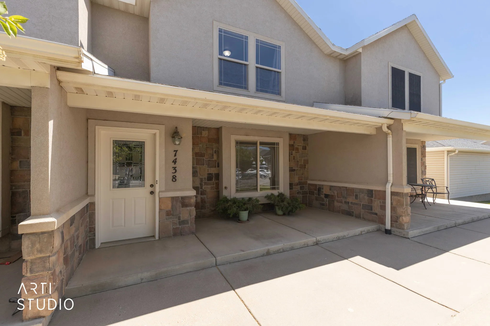 View of front of property featuring stone siding, stucco siding, and covered porch