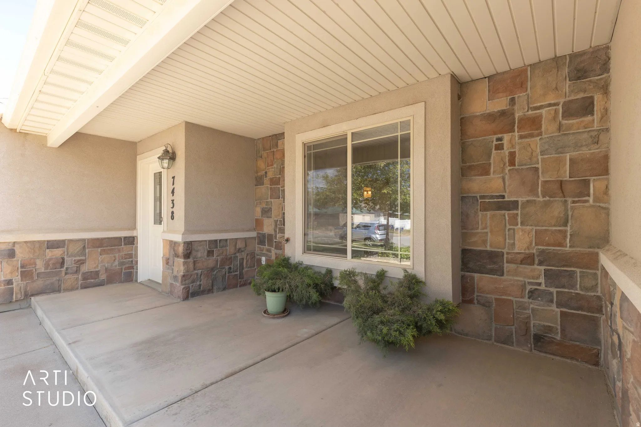 Property entrance featuring stone siding, a porch, and stucco siding