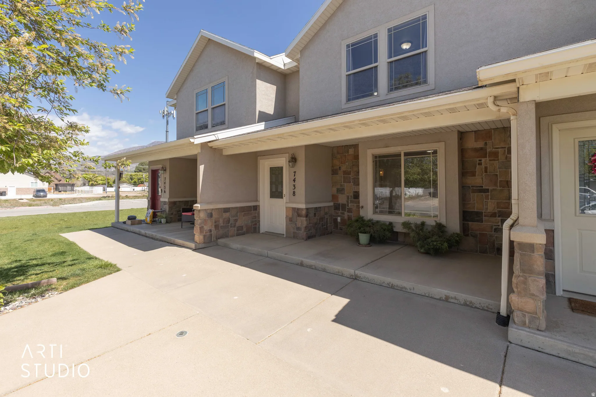 View of front of house with stone siding, a porch, and stucco siding