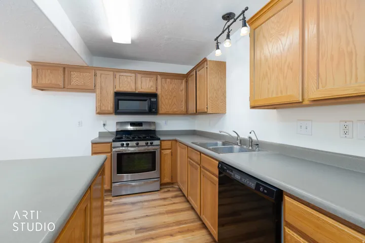 Kitchen featuring black appliances, light wood-style flooring, light countertops, a textured ceiling, and rail lighting