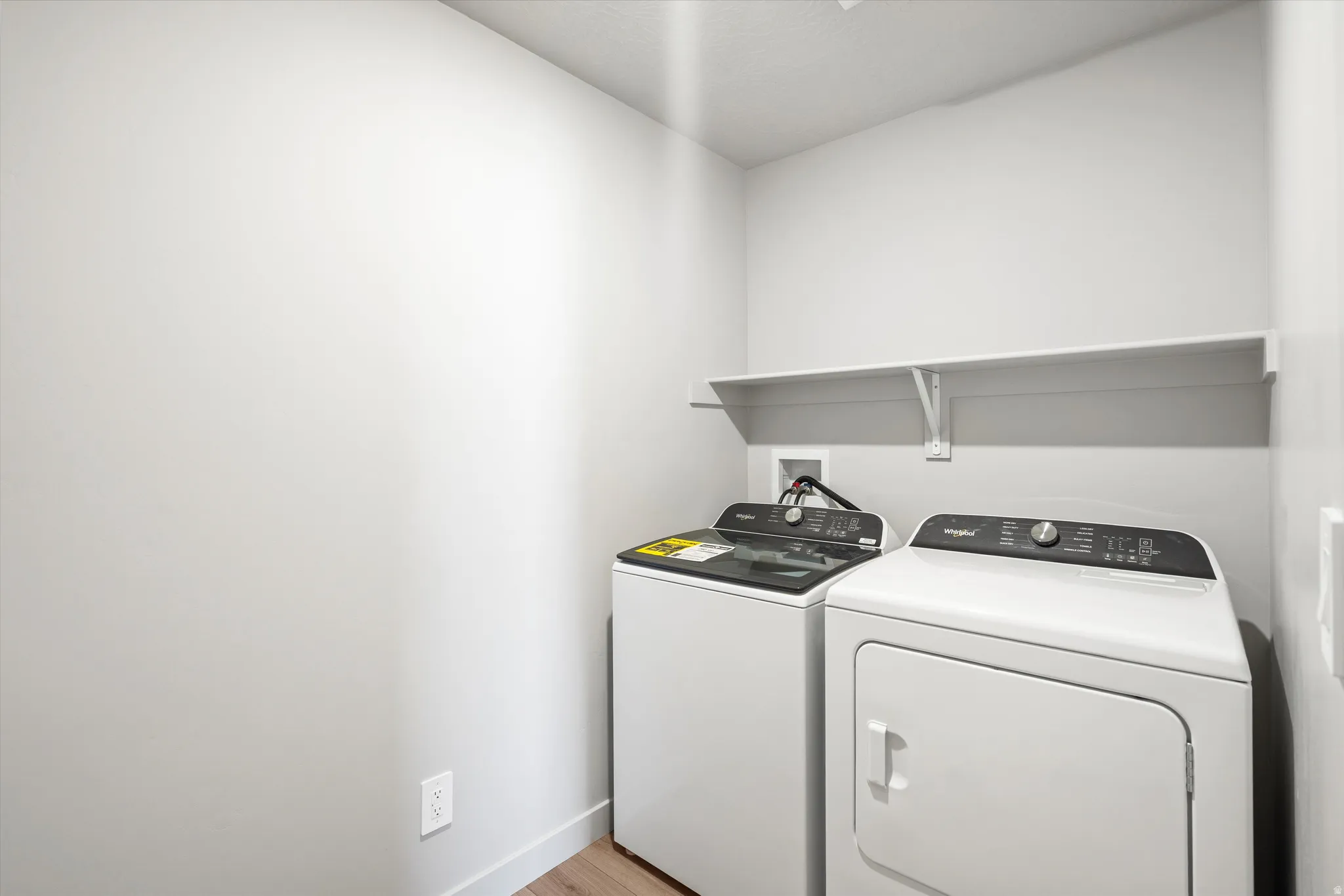 Laundry area with washer and clothes dryer and light wood finished floors