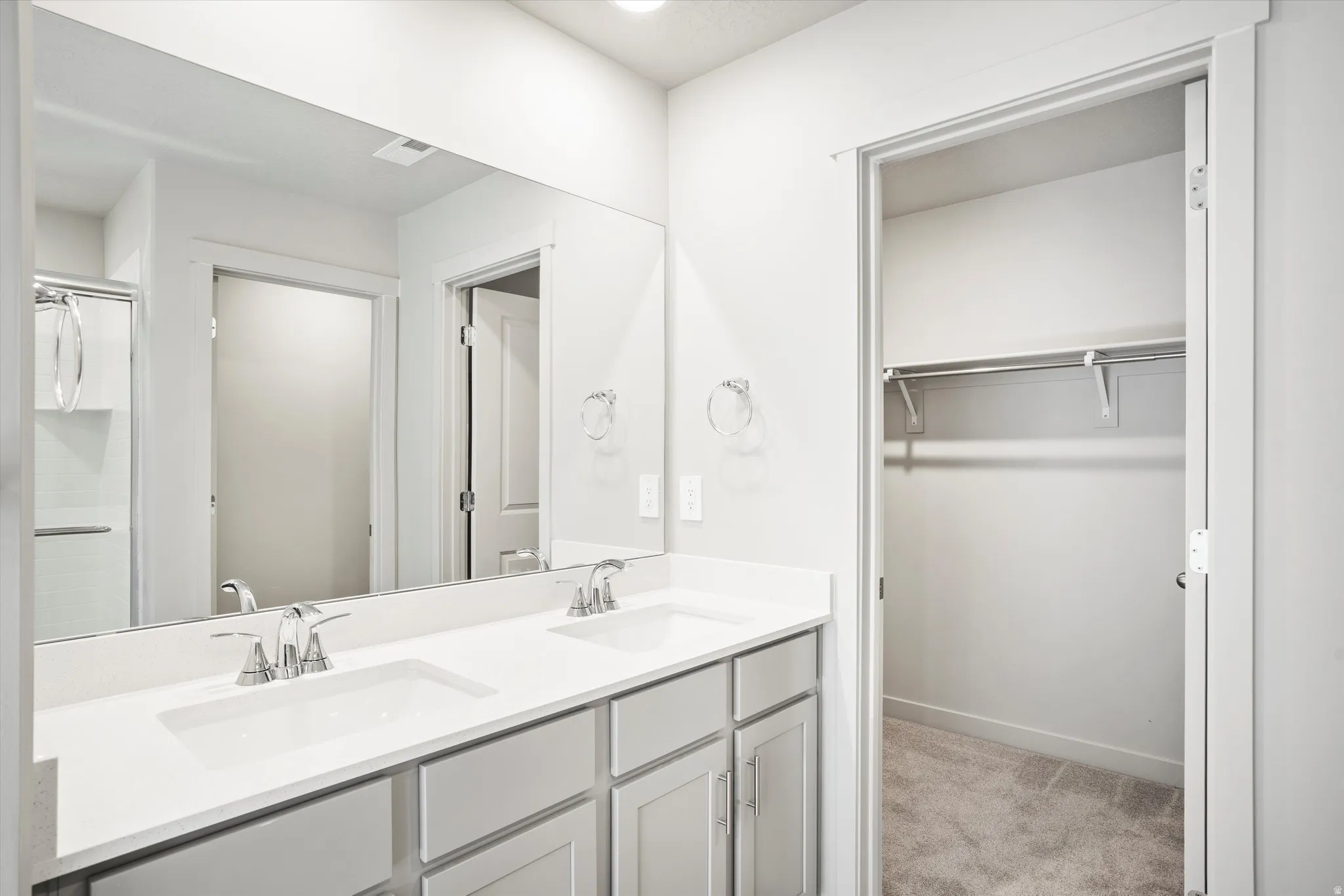 **DISCLAIMER** Interior package & color may vary. Full bathroom featuring double vanity, a spacious closet, and light carpet
