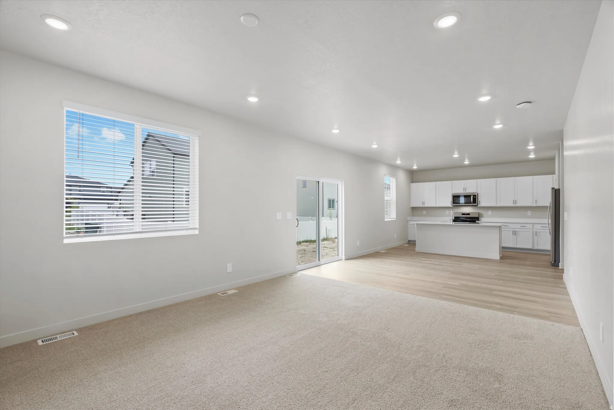 Unfurnished living room with light colored carpet and recessed lighting