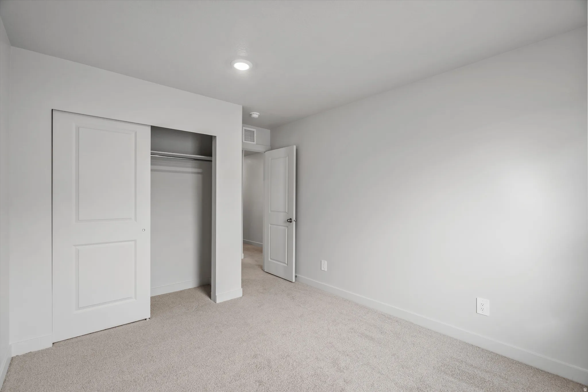 Unfurnished bedroom featuring light colored carpet and a closet