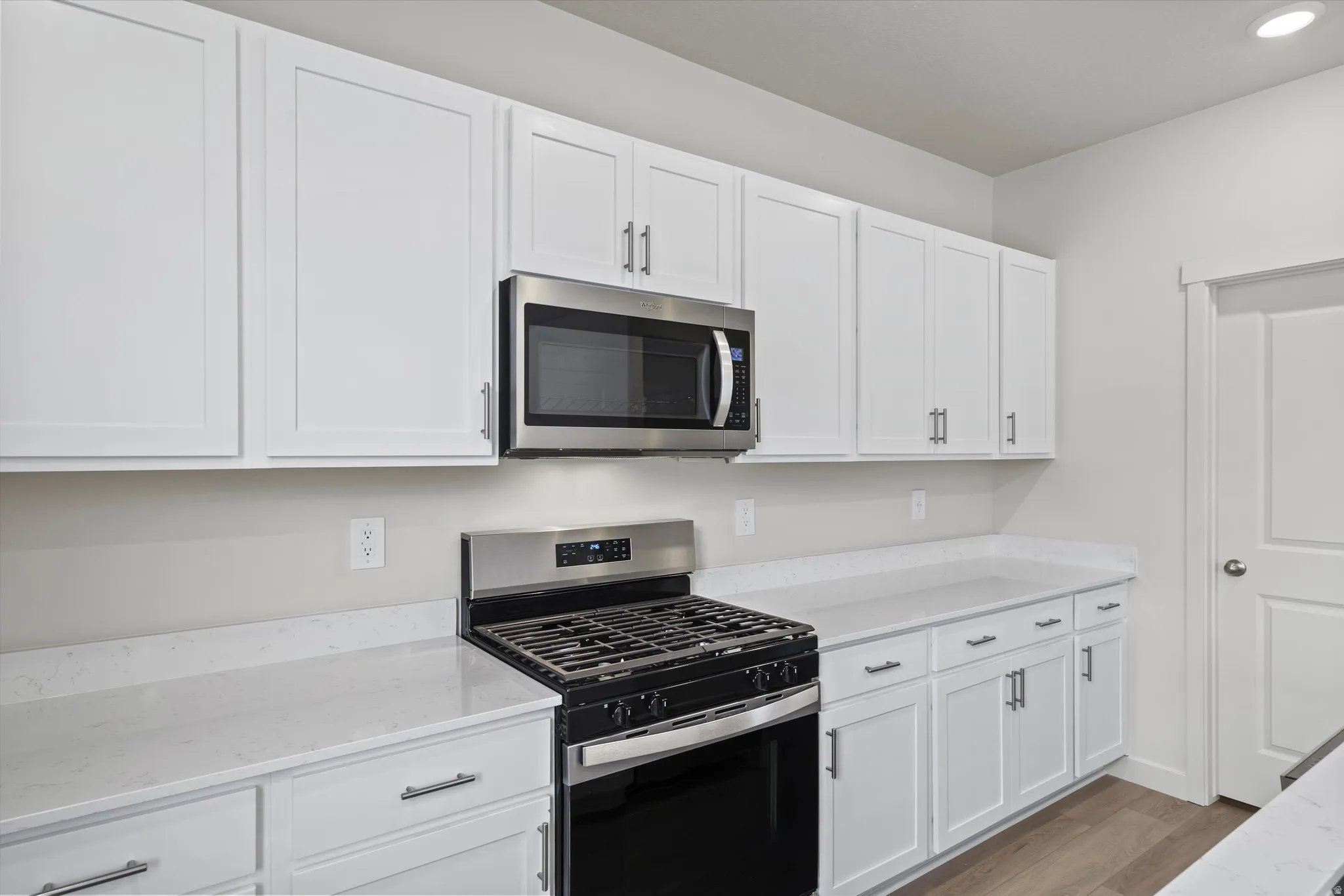Kitchen with stainless steel appliances, white cabinets, and light stone countertops