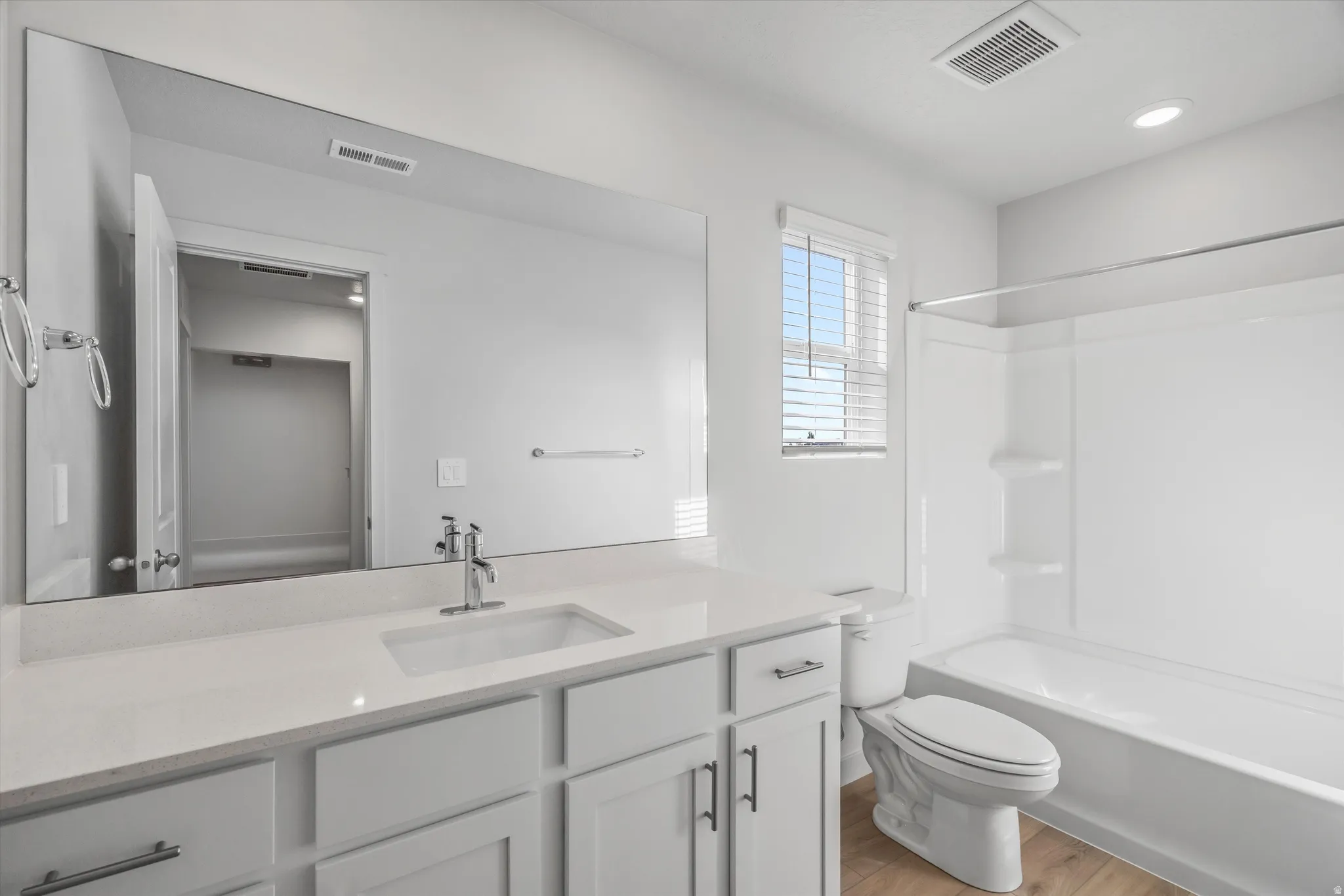 Bathroom featuring vanity, light wood finished floors, shower / washtub combination, and recessed lighting