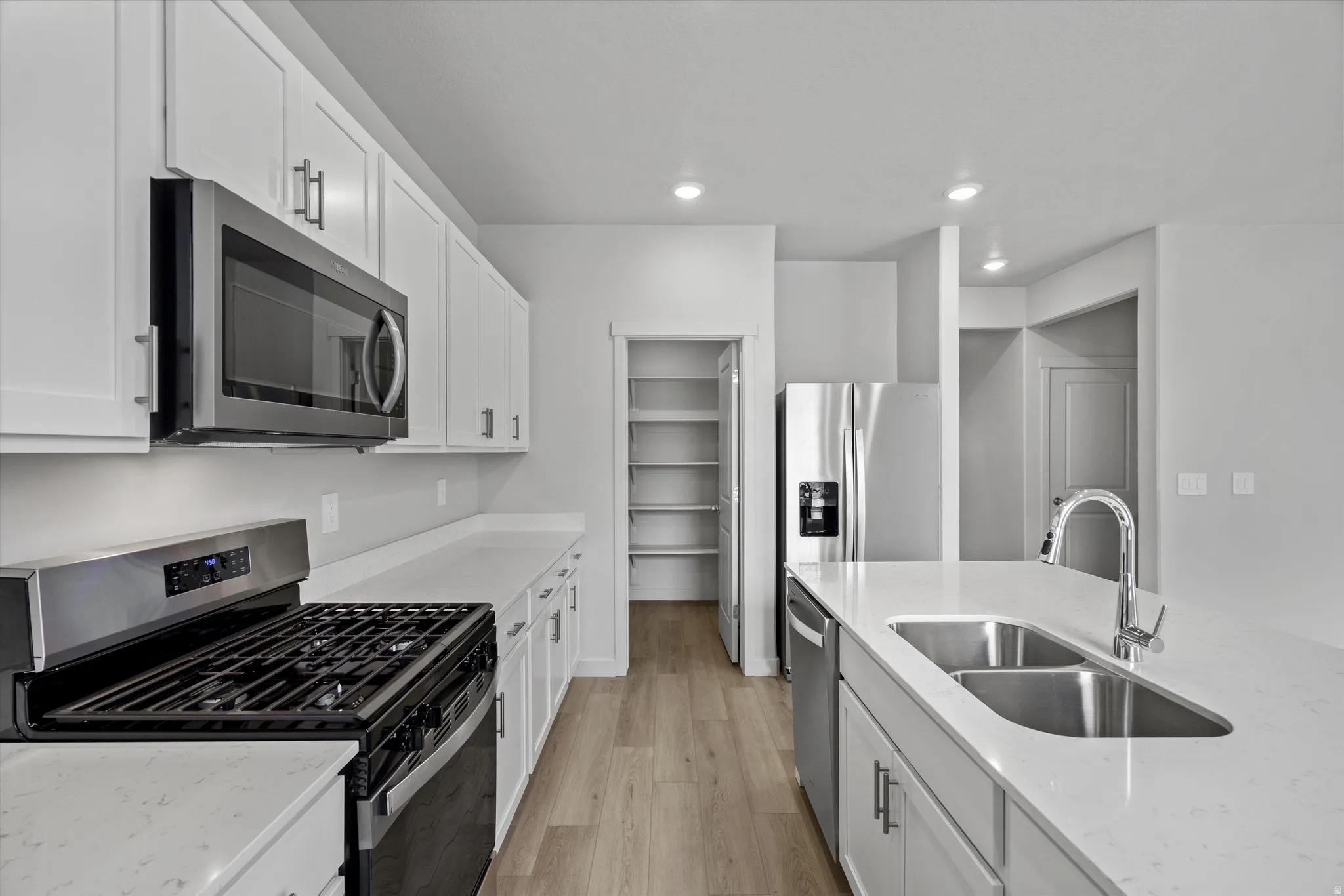Kitchen featuring stainless steel appliances, white cabinets, light wood-style floors, and recessed lighting