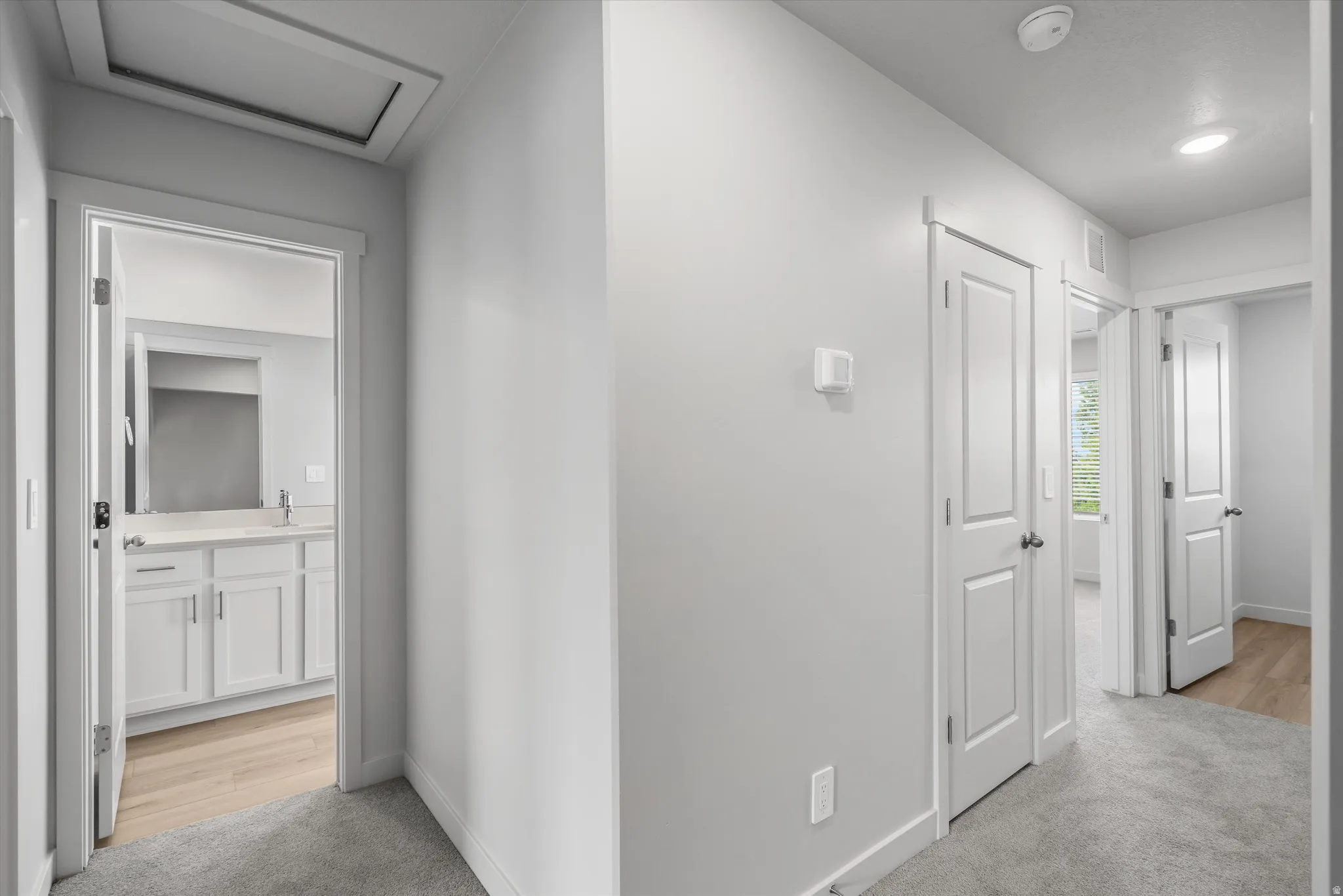 Corridor with light colored carpet and attic access