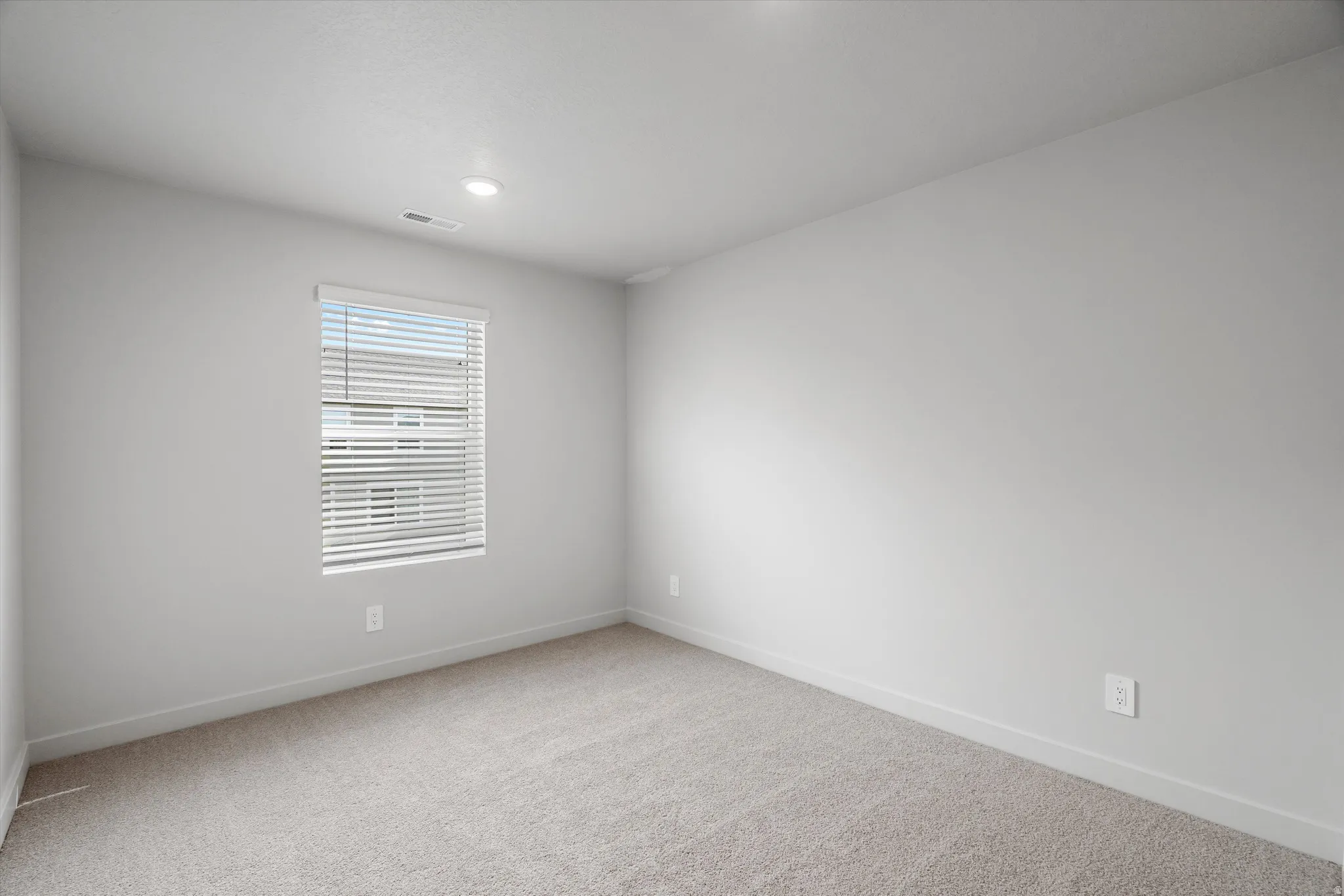 Empty room featuring light colored carpet and baseboards