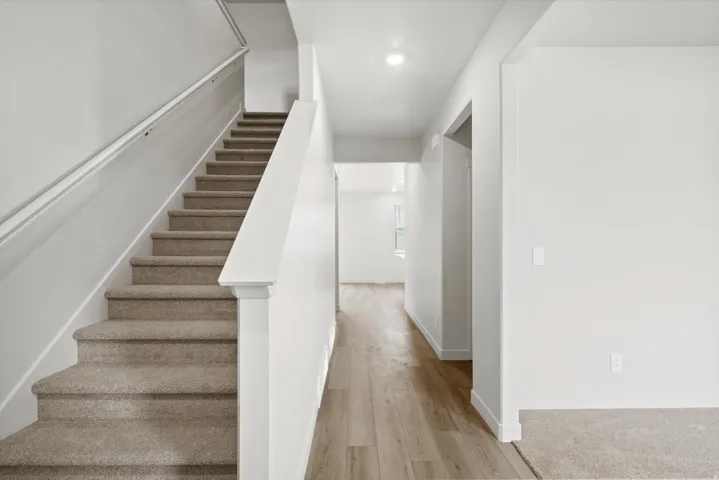 Stairway featuring wood finished floors and recessed lighting