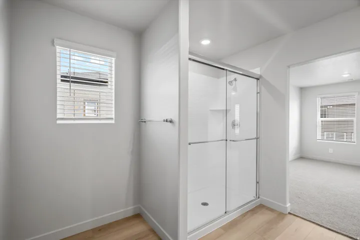 Full bath featuring a stall shower and light wood-style floors