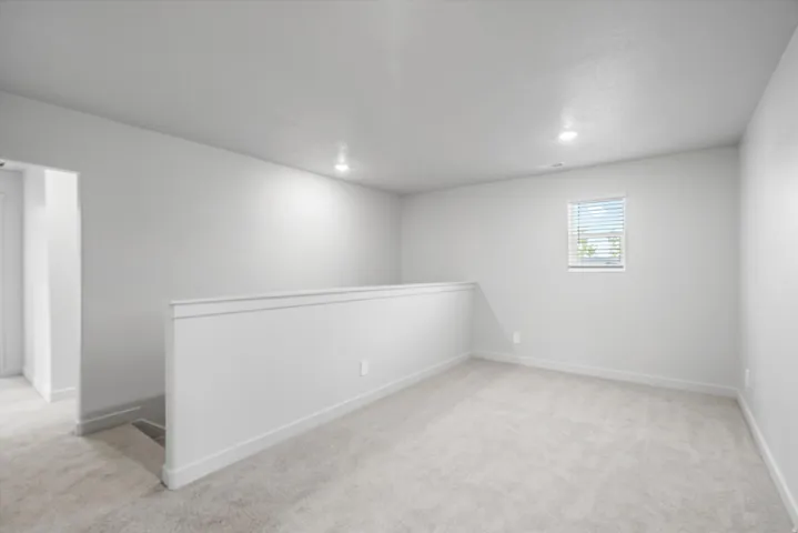 Empty room with light carpet and recessed lighting