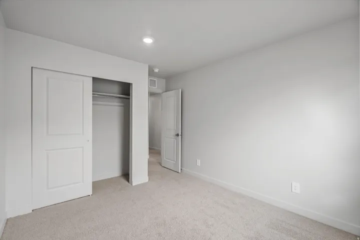 Unfurnished bedroom featuring light colored carpet and a closet