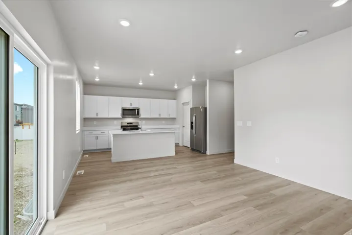 Kitchen with light countertops, white cabinetry, a kitchen island with sink, light wood finished floors, and recessed lighting