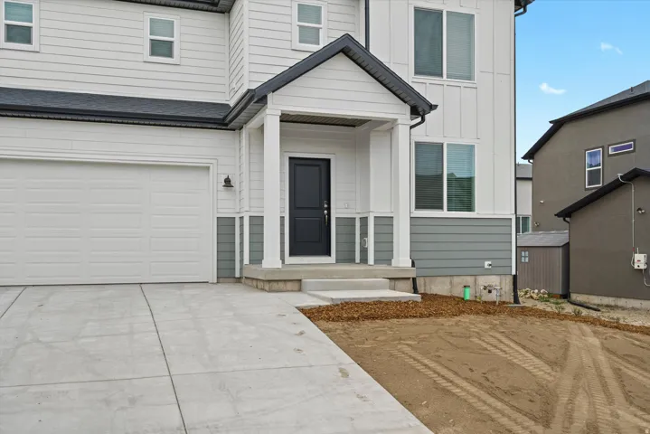 Doorway to property featuring board and batten siding, driveway, and an attached garage
