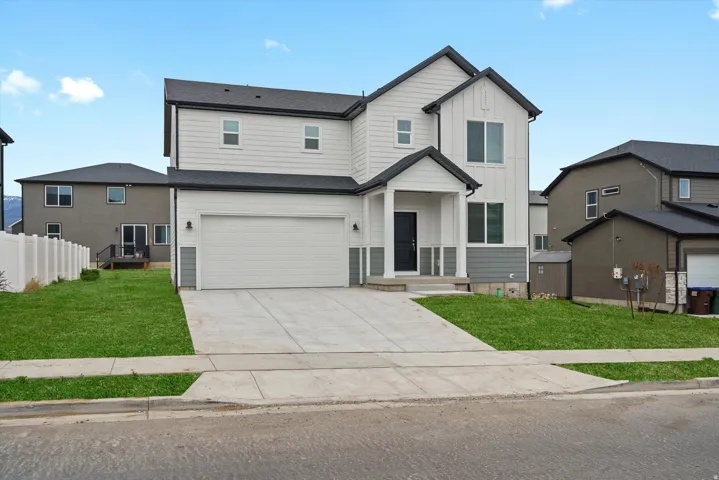 View of front of property with board and batten siding, concrete driveway, and a garage