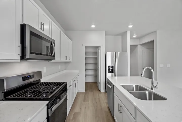 Kitchen featuring stainless steel appliances, white cabinets, light wood-style floors, and recessed lighting