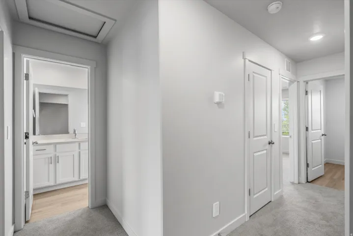 Corridor with light colored carpet and attic access