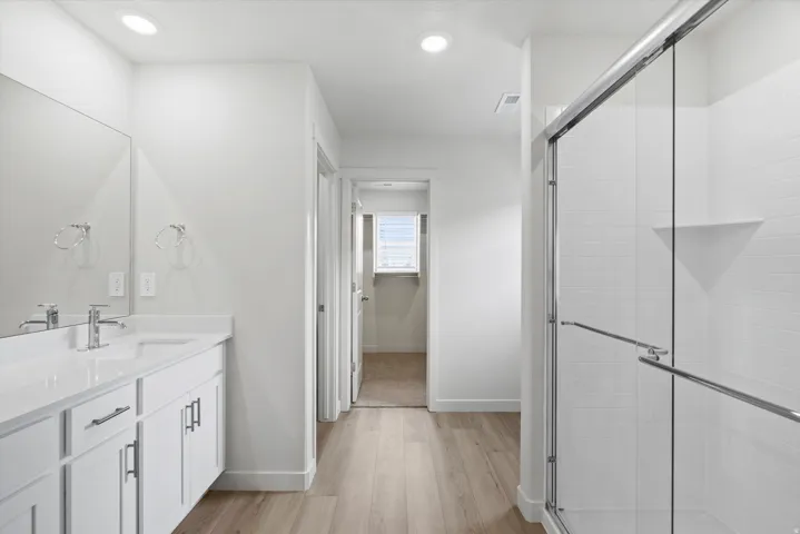 Full bathroom with a shower stall, vanity, light wood-style flooring, and recessed lighting