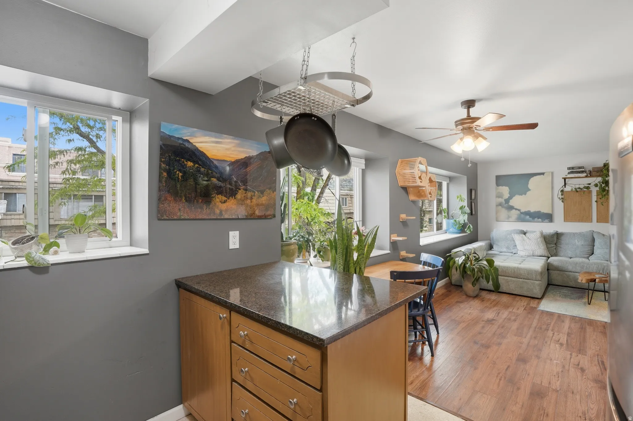Kitchen featuring healthy amount of natural light, dark stone counters, a peninsula, and ceiling fan