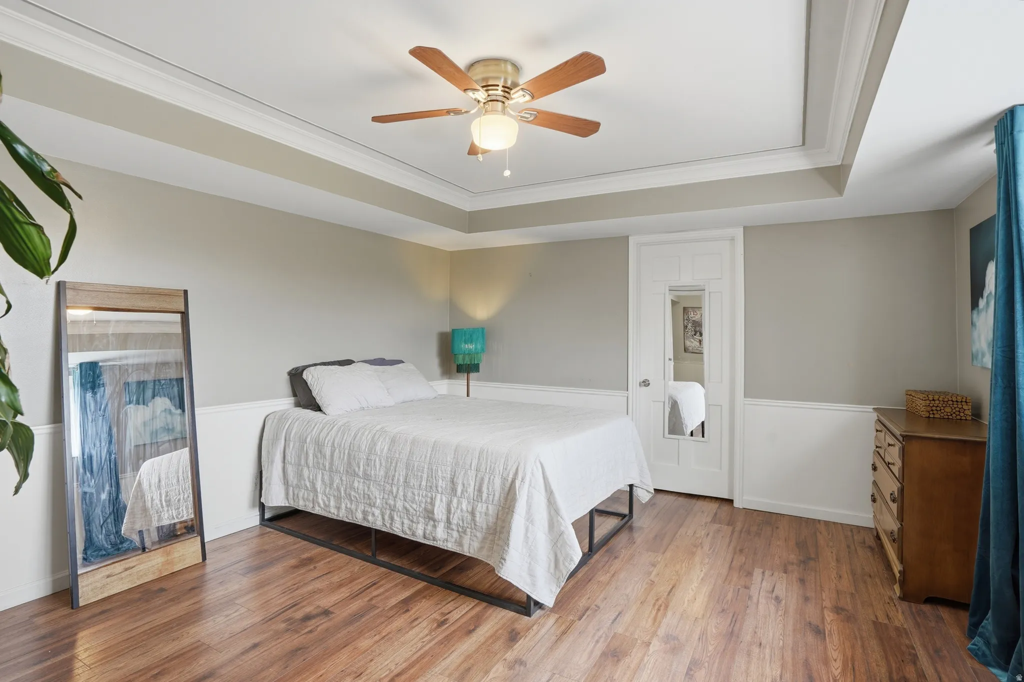 Bedroom featuring crown molding, wood finished floors, a ceiling fan, and a raised ceiling