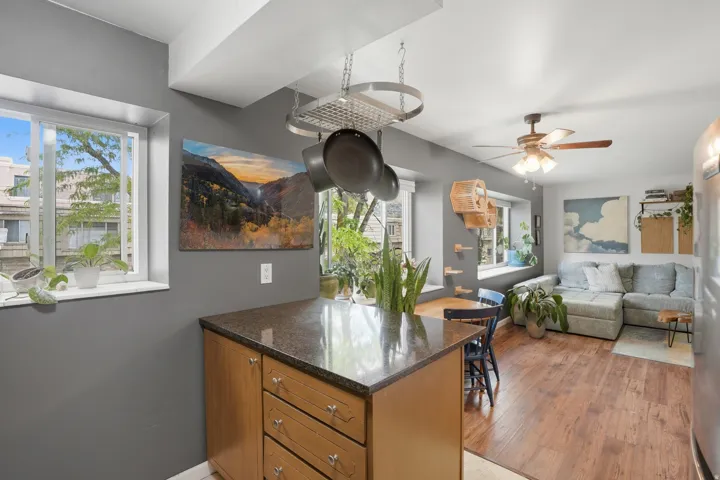 Kitchen featuring healthy amount of natural light, dark stone counters, a peninsula, and ceiling fan