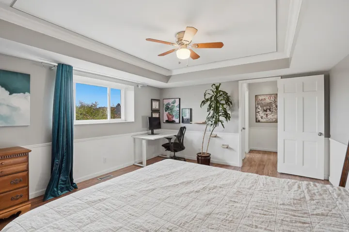 Bedroom with wood finished floors, a ceiling fan, ornamental molding, and a desk