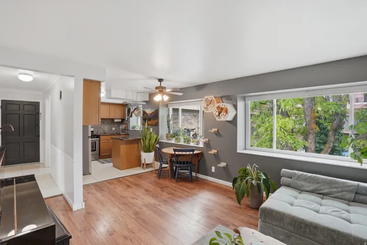 Living room with light wood-style flooring, a ceiling fan, and crown molding