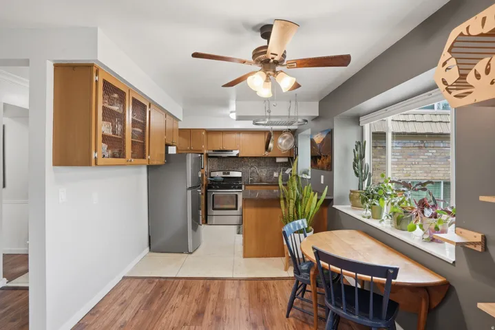 Kitchen with glass fronted cabinets, light wood finished floors, stainless steel appliances, backsplash, and wood finish cabinetry