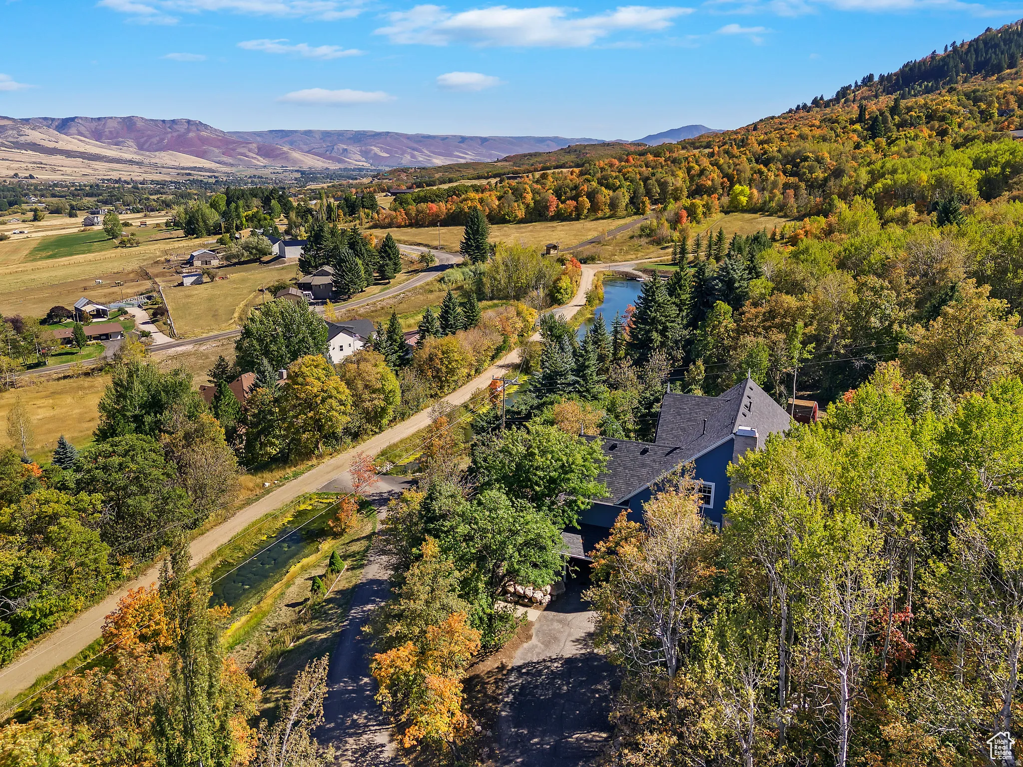 Aerial perspective showcasing a property surrounded by mature trees with autumnal foliage