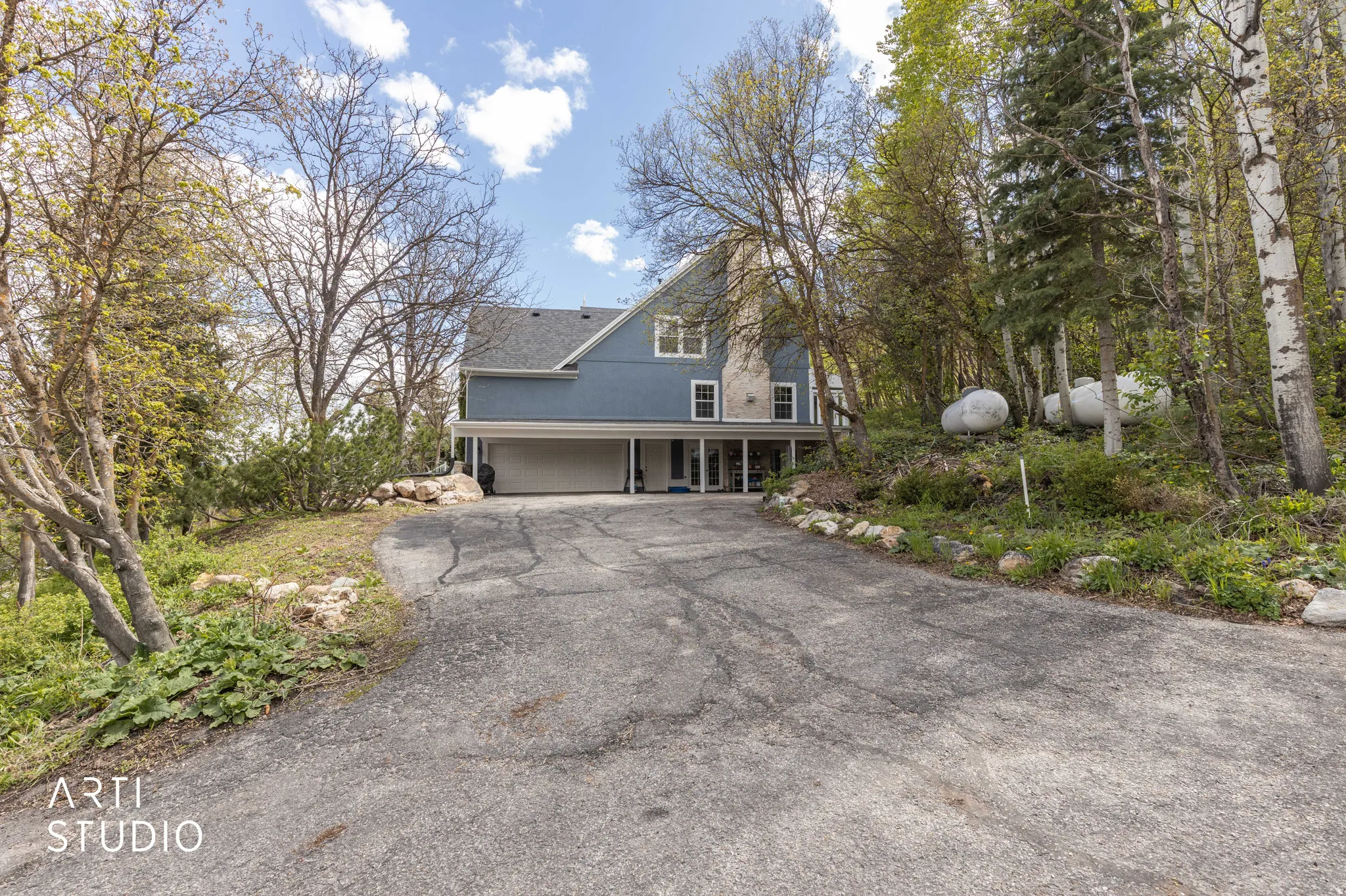 View of front of house with asphalt driveway, covered porch, and a garage