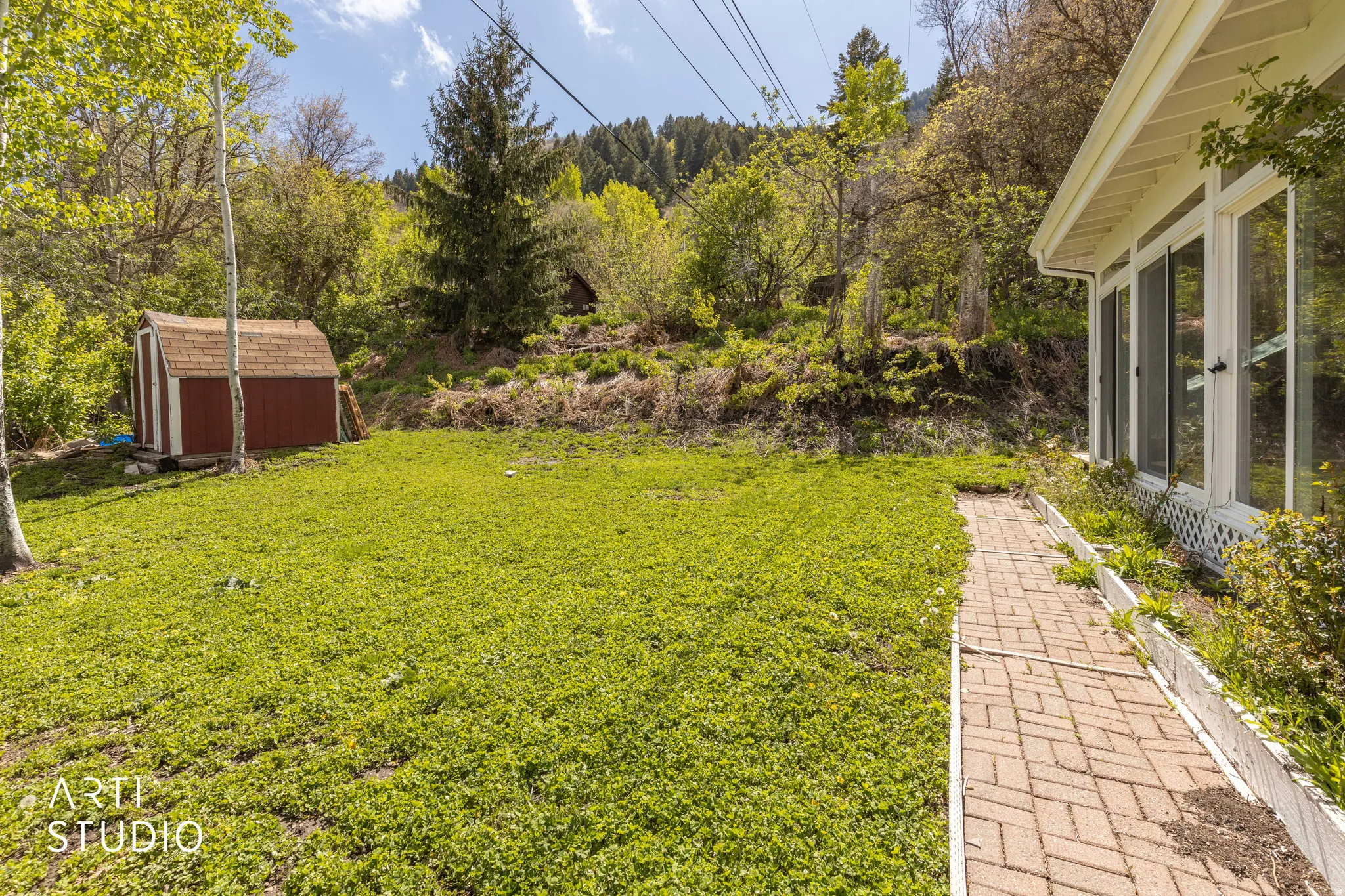 View of grassy yard featuring a storage shed and a sunroom