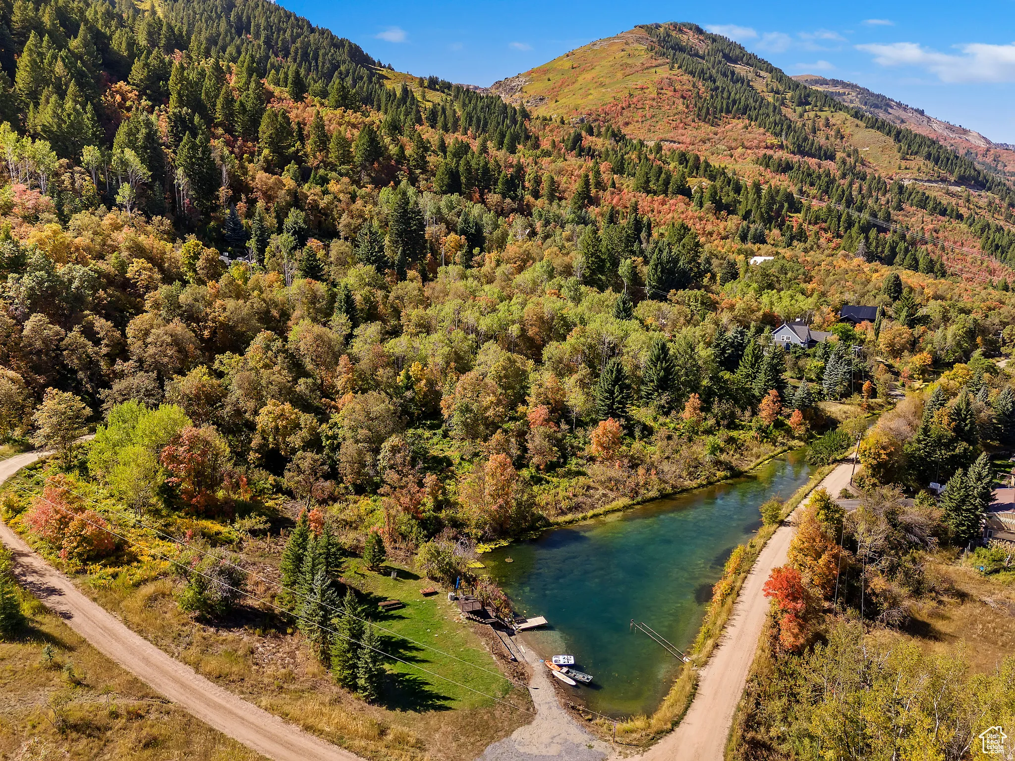 Mountainous landscape featuring a prominent pond with small docks and boats, surrounded by diverse foliage