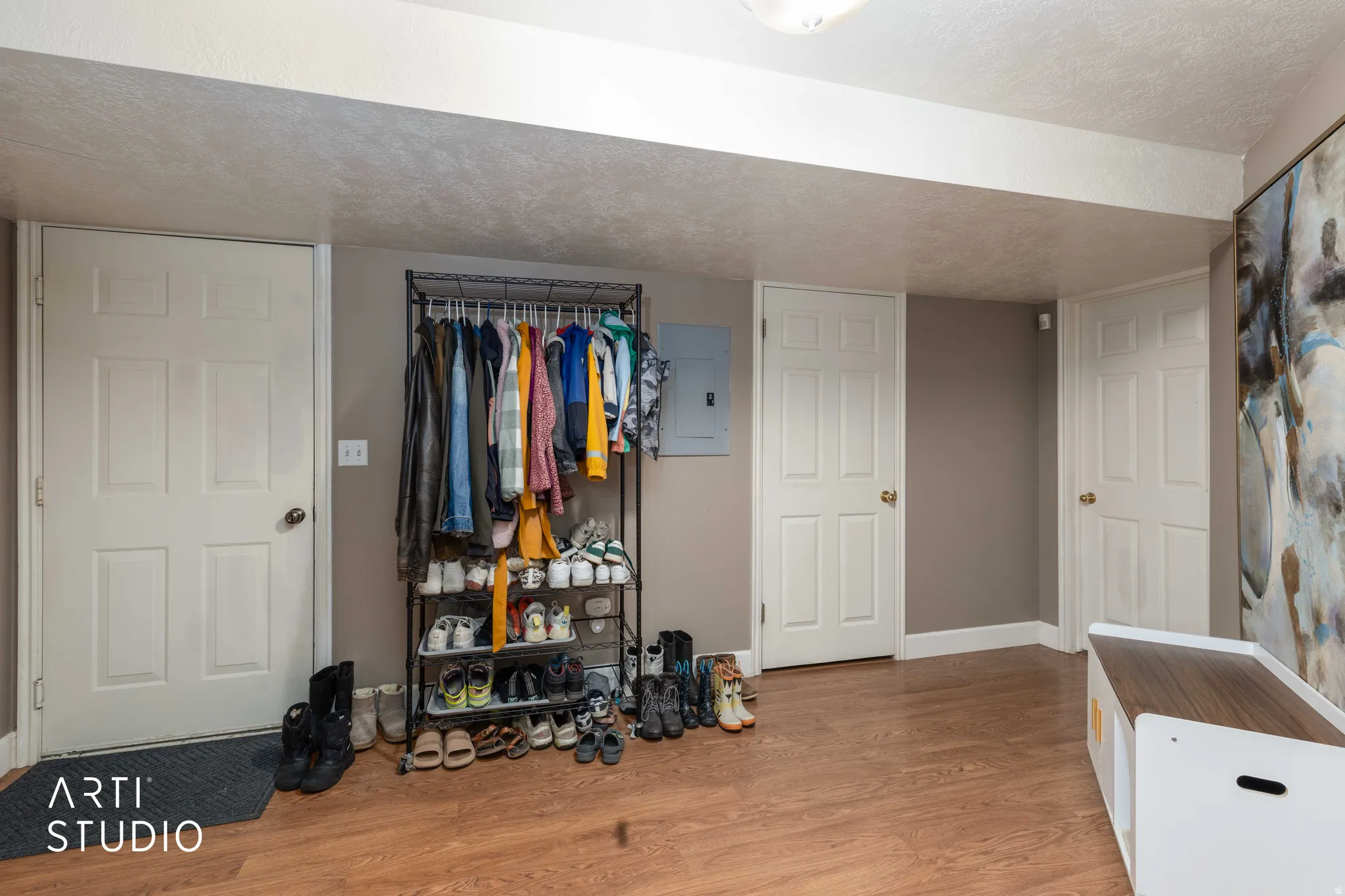 Bedroom with a textured ceiling, light wood-style floors, and electric panel