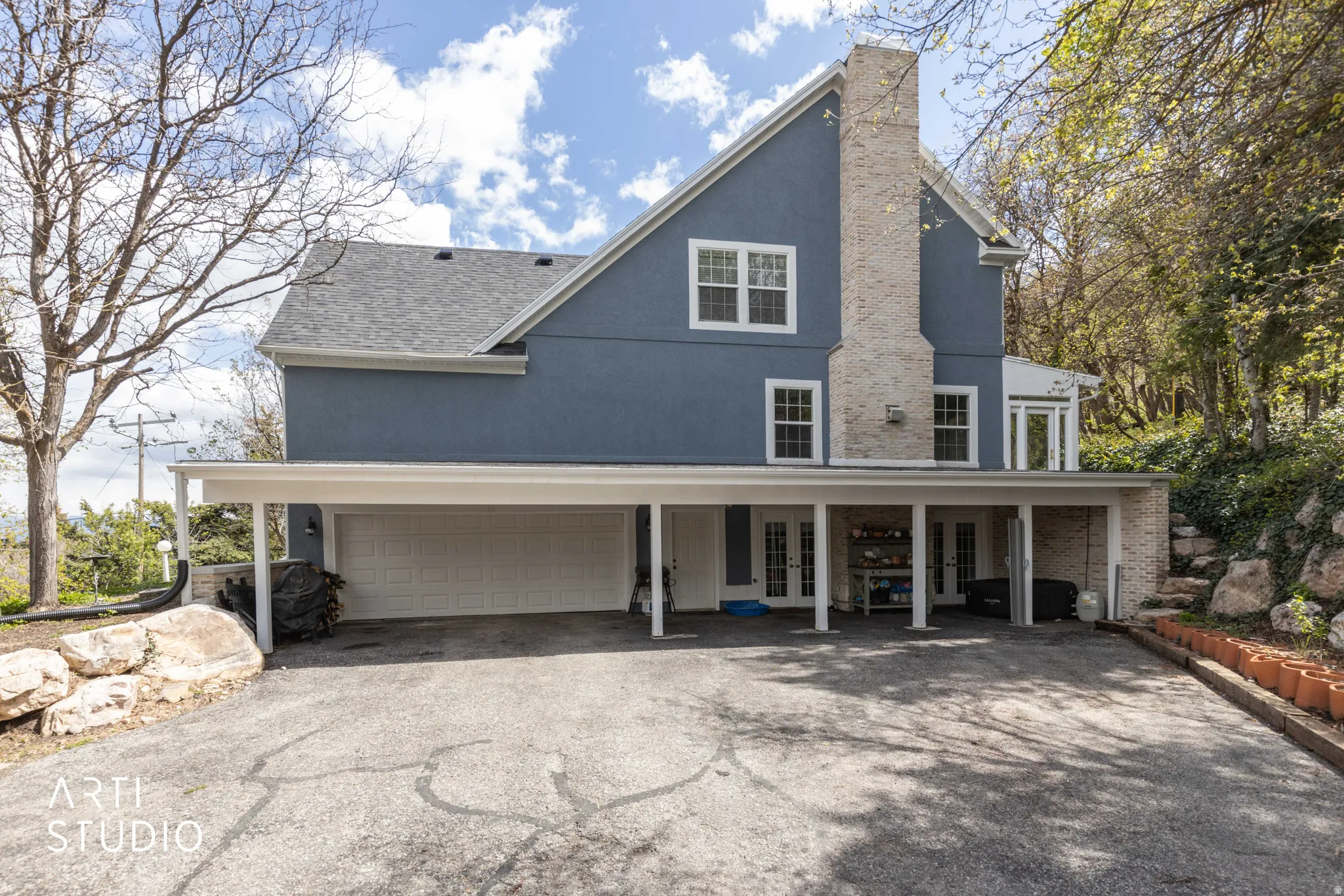 View of front of home featuring asphalt driveway, french doors, stucco siding, a garage, and a chimney