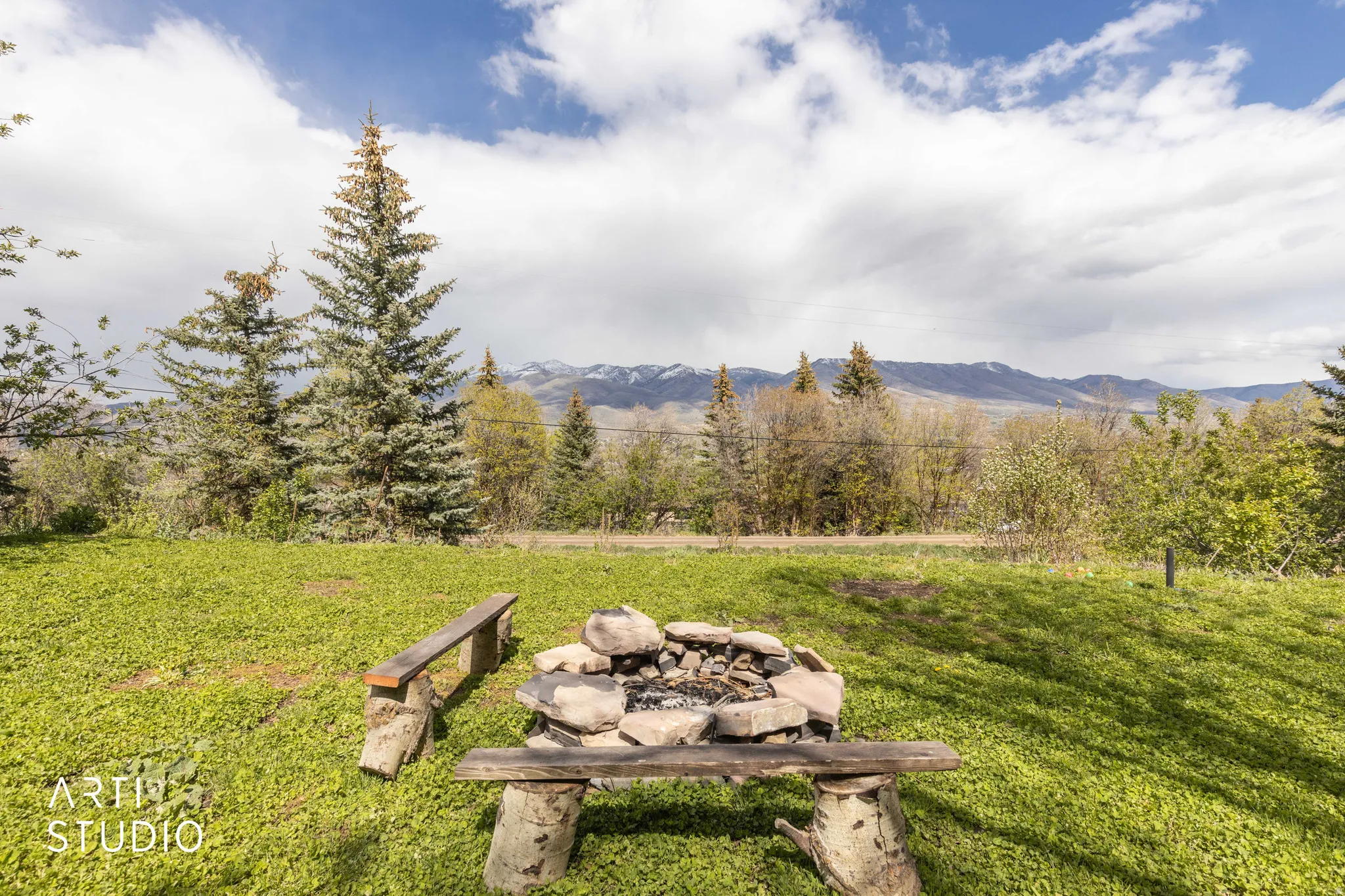 View of green lawn featuring an outdoor fire pit and a mountain view