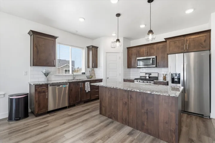 Kitchen with stainless steel appliances, light stone countertops, and dark wood finish cabinetry