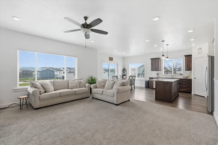 Living area with dark colored carpet, a ceiling fan, and recessed lighting