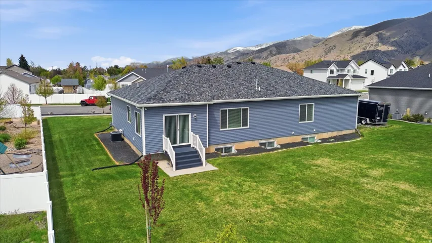 Back of property with a lawn, entry steps, a residential view, and a mountain view