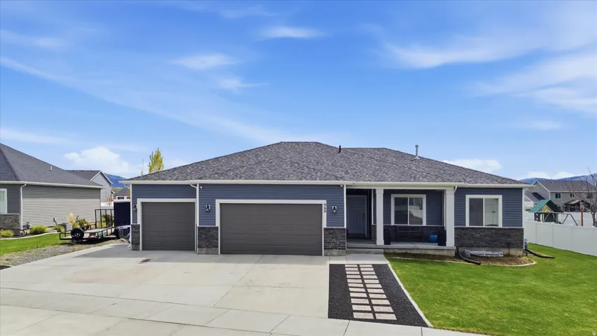 View of front facade with a garage, driveway, a porch, and stone siding