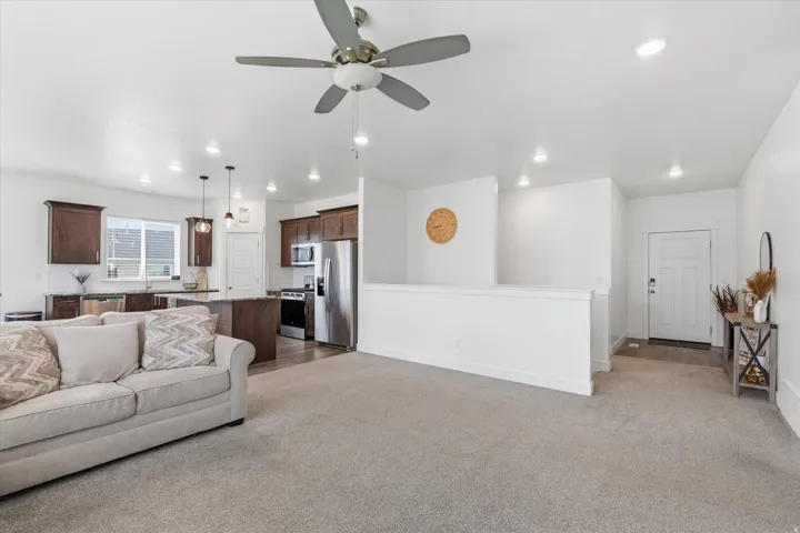 Living area featuring a ceiling fan, light colored carpet, and recessed lighting