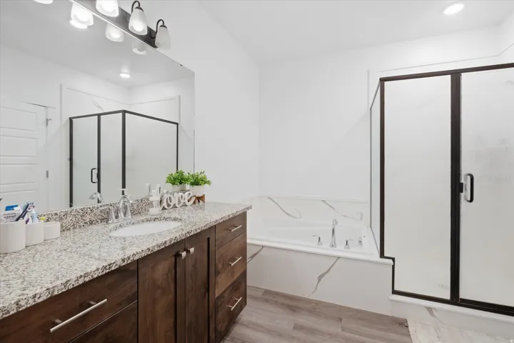 Primary Bathroom with a shower stall, vanity, light wood-style flooring, a garden tub, and recessed lighting