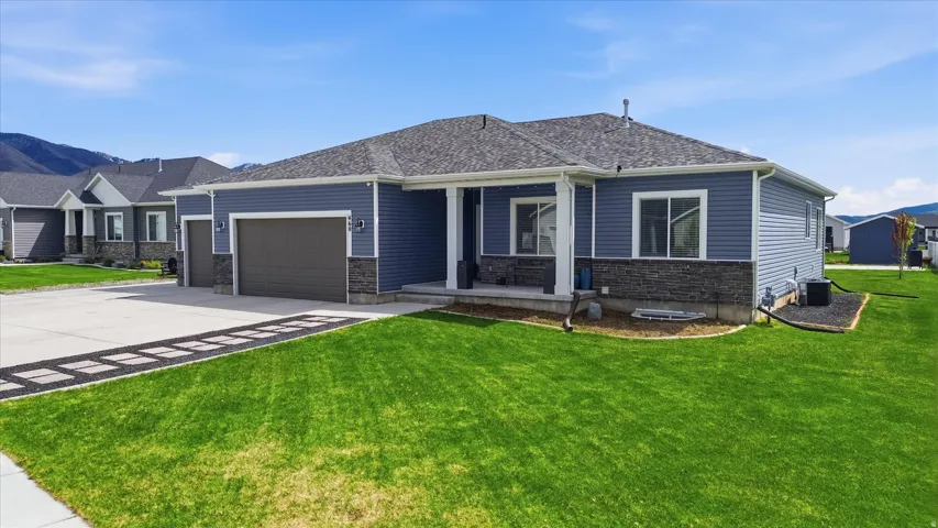 View of front facade featuring a garage, a front yard, concrete driveway, and a porch