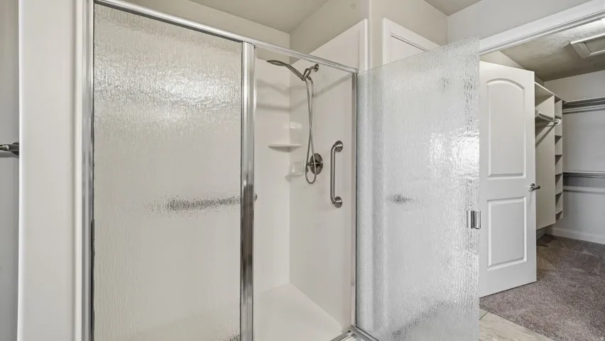 Full bathroom with a spacious closet and a stall shower