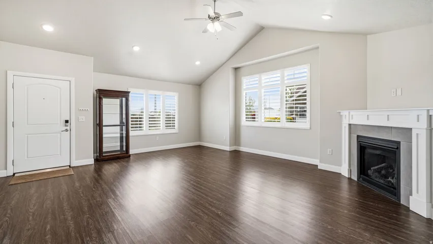 Unfurnished living room with a ceiling fan, dark wood-type flooring, a fireplace, and recessed lighting