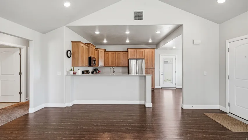 Kitchen with light countertops, a peninsula, dark wood finished floors, stainless steel appliances, and wood finish cabinets
