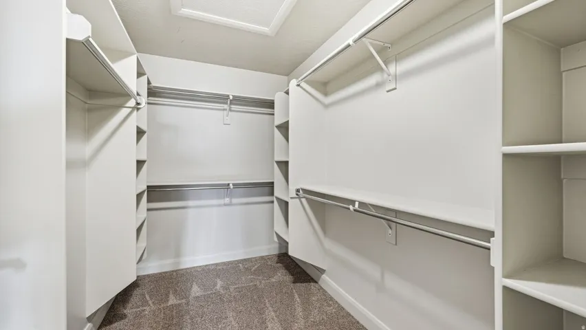 Big master Walk in closet featuring dark colored carpet