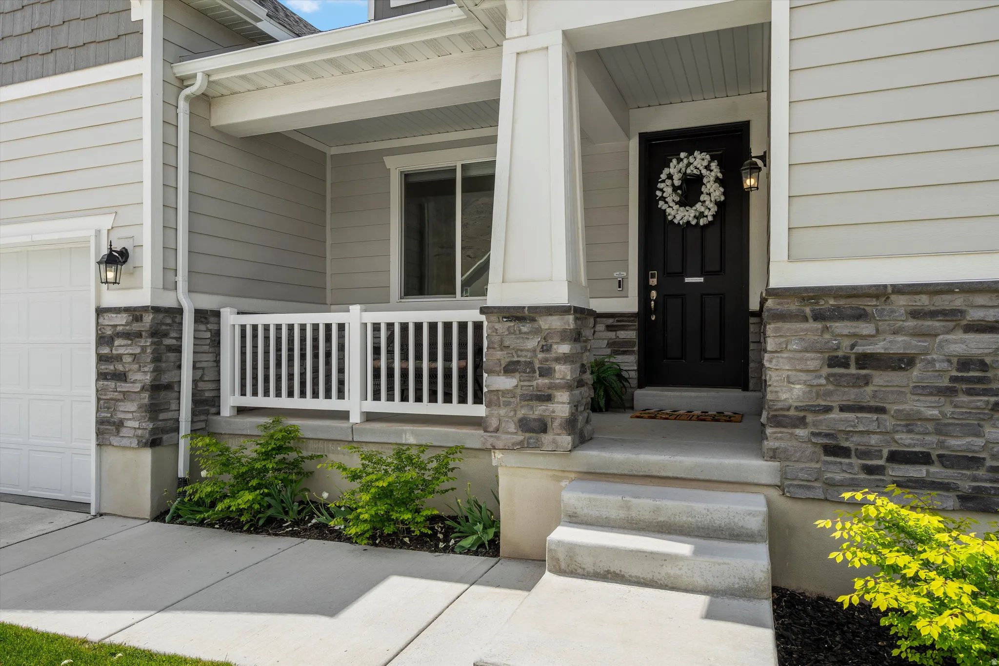 Property entrance with stone siding, a garage, and covered porch