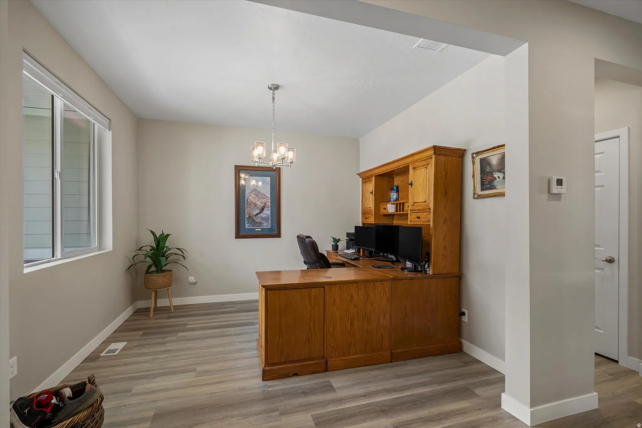 Office with light wood-style flooring and suspended lighting